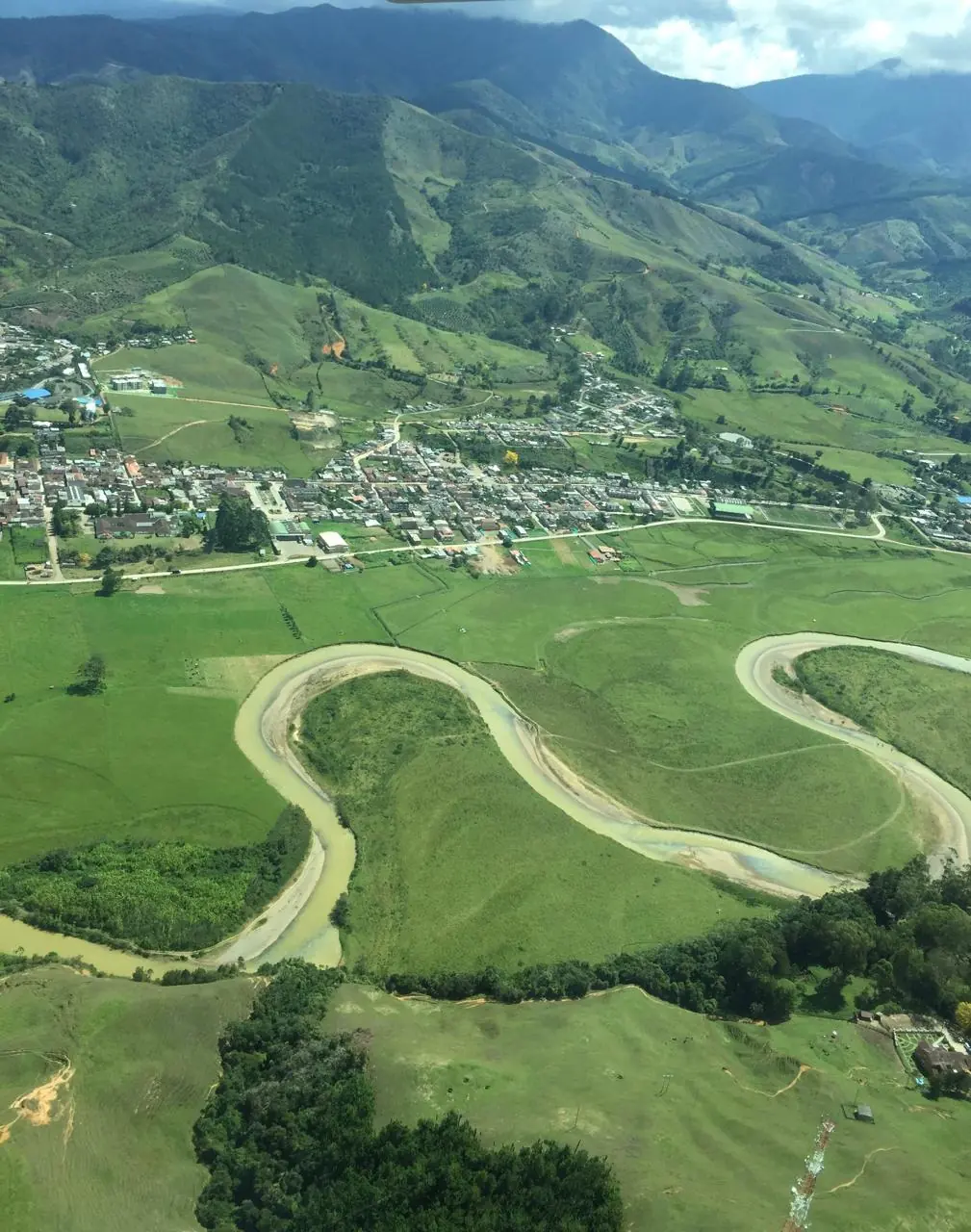 Vista aérea del valle del Suroeste de Antioquia, con un río serpenteando entre montañas y campos verdes